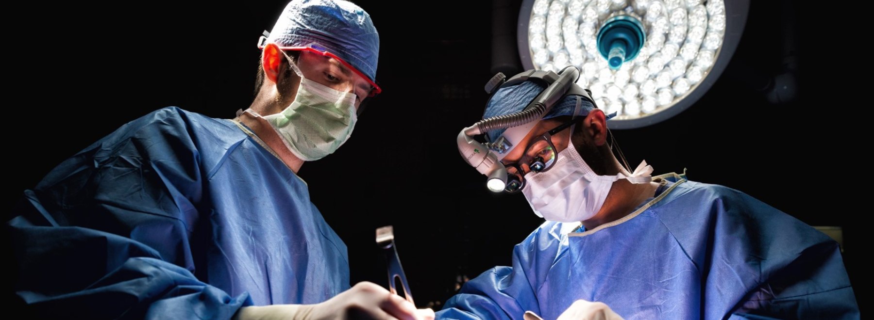 Two doctors in operating room performing surgery.